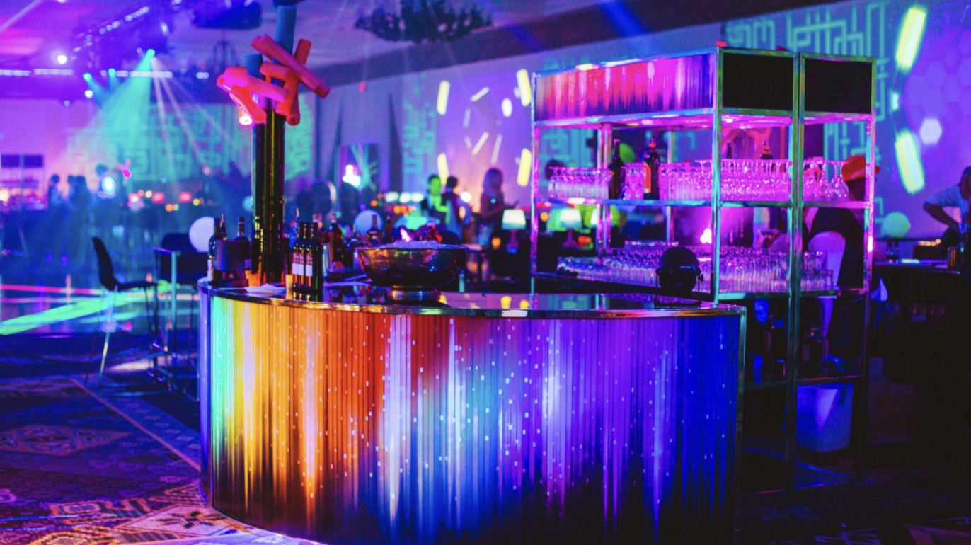 Landscape image of a colourful bar at night with neon lights.